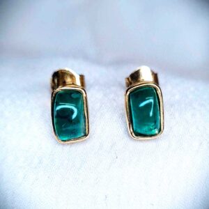 Aretes con esmeraldas naturales en corte cabujón medio, montadas en oro amarillo de 18K. Diseño artesanal colombiano.